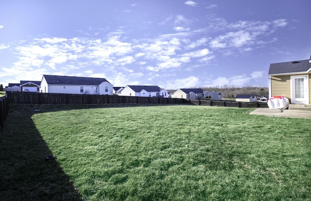 view of yard featuring a residential view, a fenced backyard, and a patio area