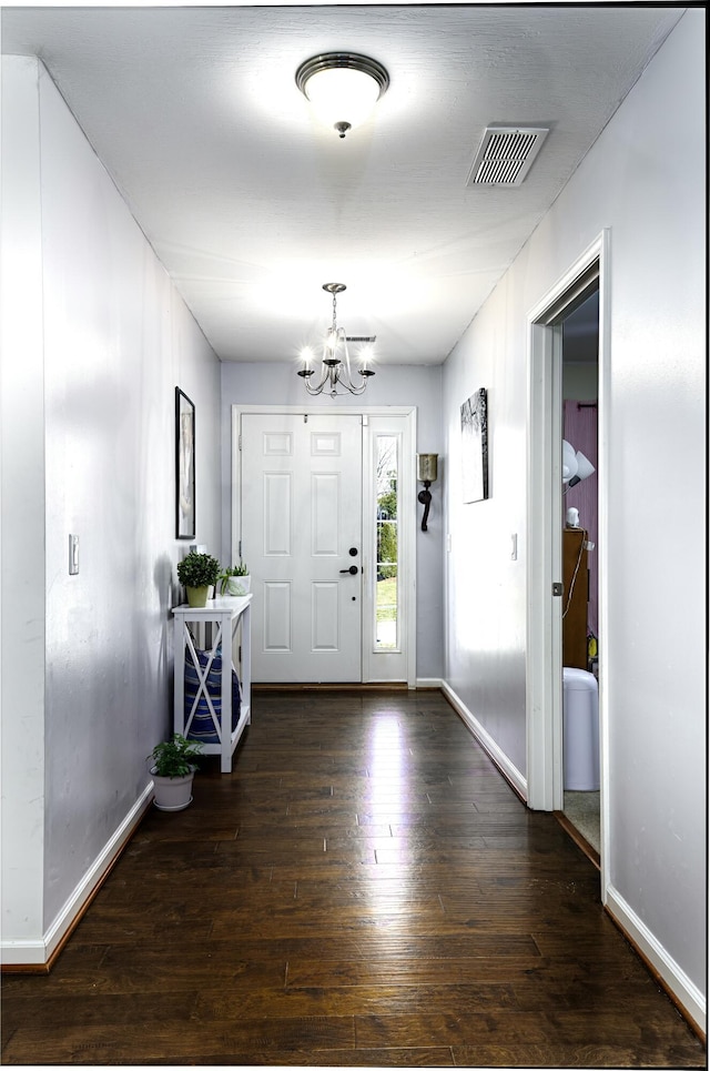 entrance foyer with visible vents, baseboards, an inviting chandelier, and wood-type flooring