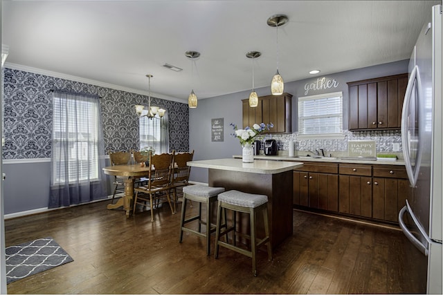 kitchen featuring visible vents, dark wood-style floors, a center island, and freestanding refrigerator