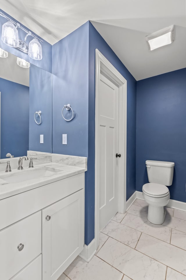 bathroom featuring marble finish floor, toilet, vanity, and baseboards