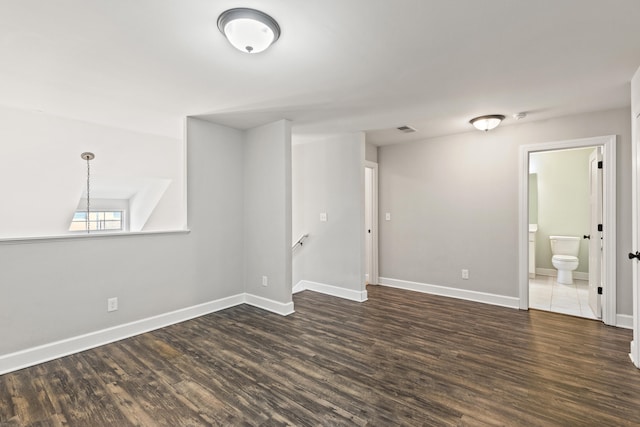 unfurnished room featuring baseboards and dark wood-style floors