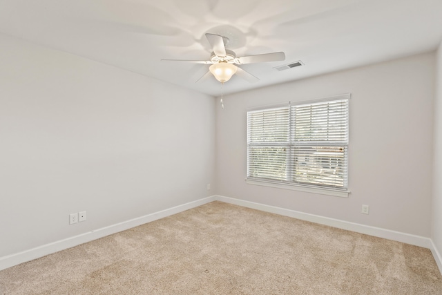 carpeted spare room featuring visible vents, baseboards, and ceiling fan