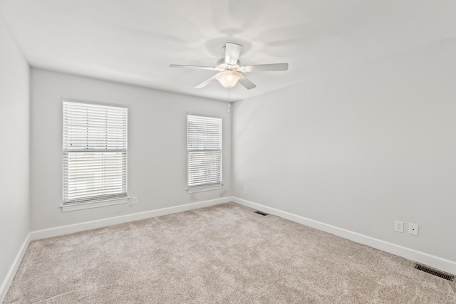 carpeted empty room with visible vents, a ceiling fan, and baseboards