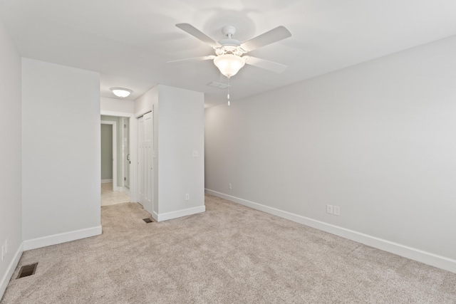 empty room with visible vents, light colored carpet, baseboards, and ceiling fan