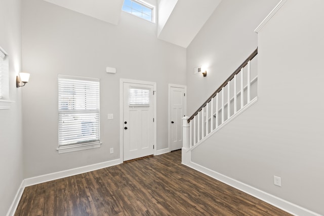 foyer with stairway, baseboards, a high ceiling, and dark wood-type flooring