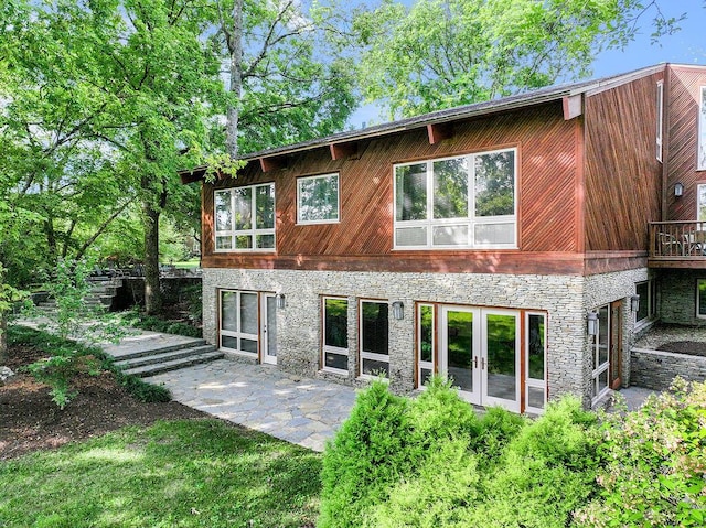 rear view of house with french doors, stone siding, and a patio area