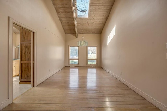 spare room featuring baseboards, high vaulted ceiling, wood ceiling, a notable chandelier, and light wood-type flooring