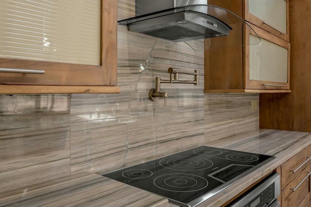 kitchen with wall oven, backsplash, ventilation hood, brown cabinetry, and stove