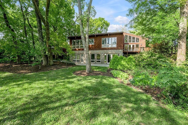 back of house featuring stone siding and a lawn