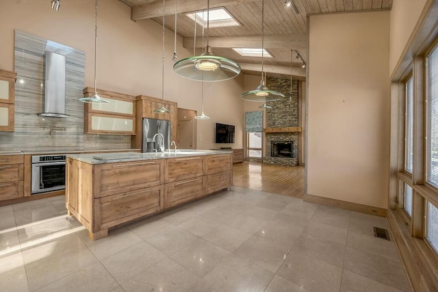 kitchen featuring tasteful backsplash, wooden ceiling, a skylight, stainless steel appliances, and wall chimney exhaust hood