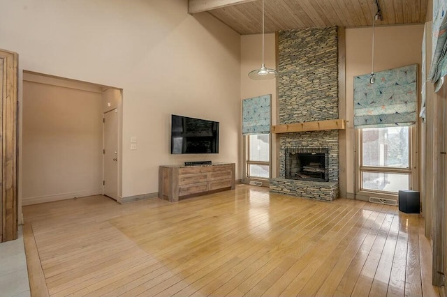 unfurnished living room featuring beamed ceiling, plenty of natural light, light wood-style flooring, and a fireplace