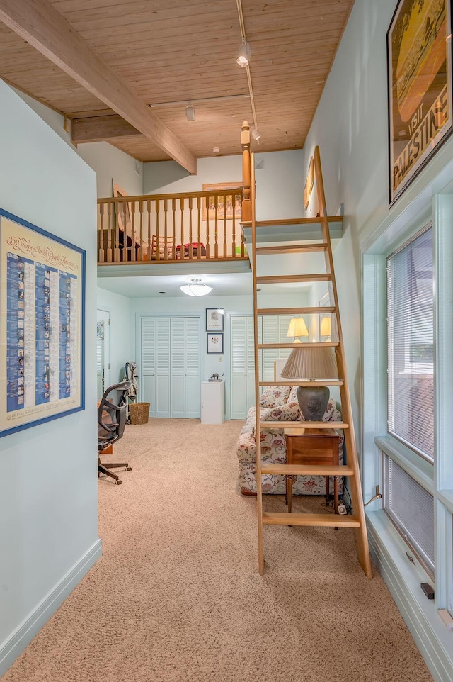 interior space featuring beam ceiling, carpet, baseboards, wood ceiling, and stairs