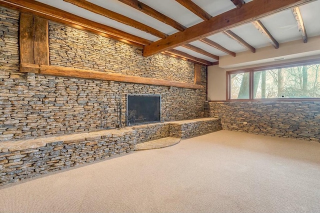 interior space featuring carpet floors, beam ceiling, and a fireplace