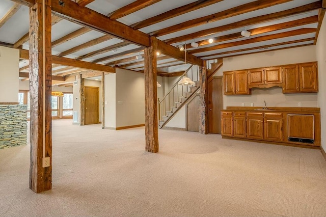 below grade area featuring indoor wet bar, stairway, light carpet, and a sink