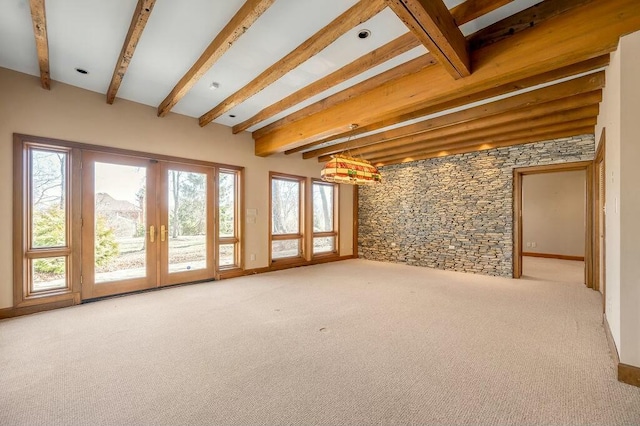 carpeted spare room featuring beamed ceiling and french doors