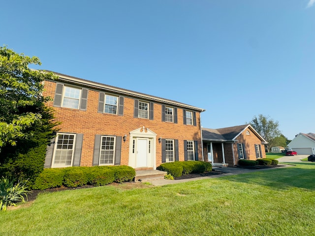 colonial inspired home with a front yard and brick siding