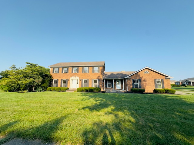 colonial-style house featuring brick siding and a front lawn