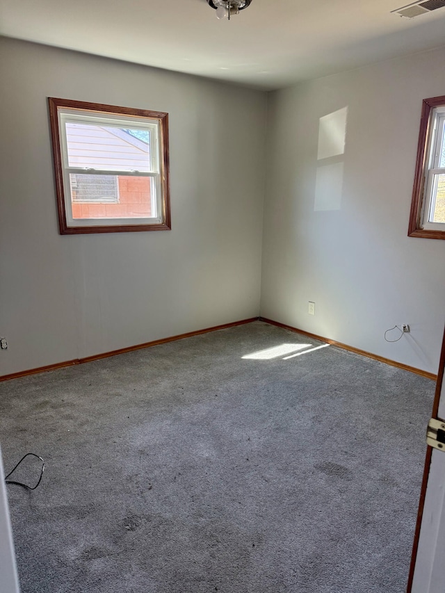 spare room featuring visible vents, plenty of natural light, carpet, and baseboards