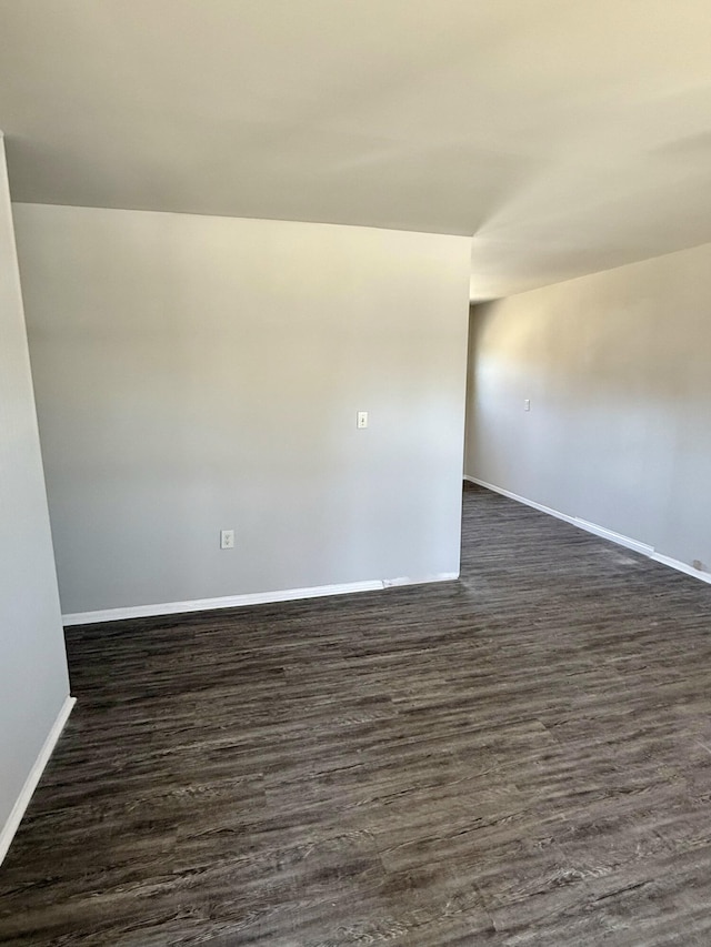 unfurnished room with baseboards and dark wood-type flooring