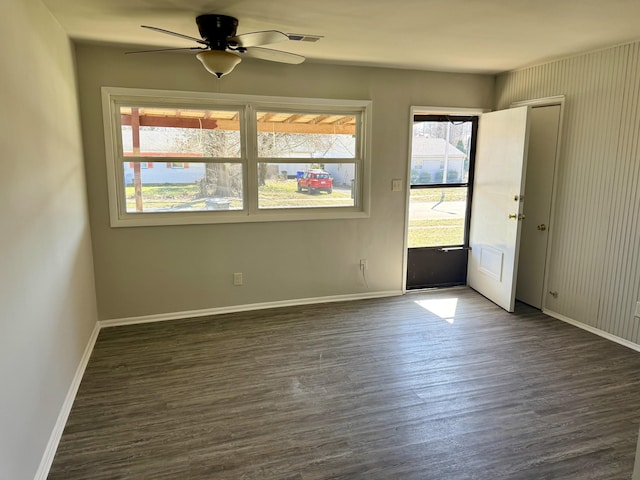 spare room featuring baseboards, ceiling fan, and dark wood-style flooring