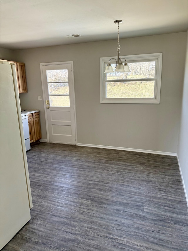 unfurnished dining area with a notable chandelier, dark wood-style floors, visible vents, and baseboards