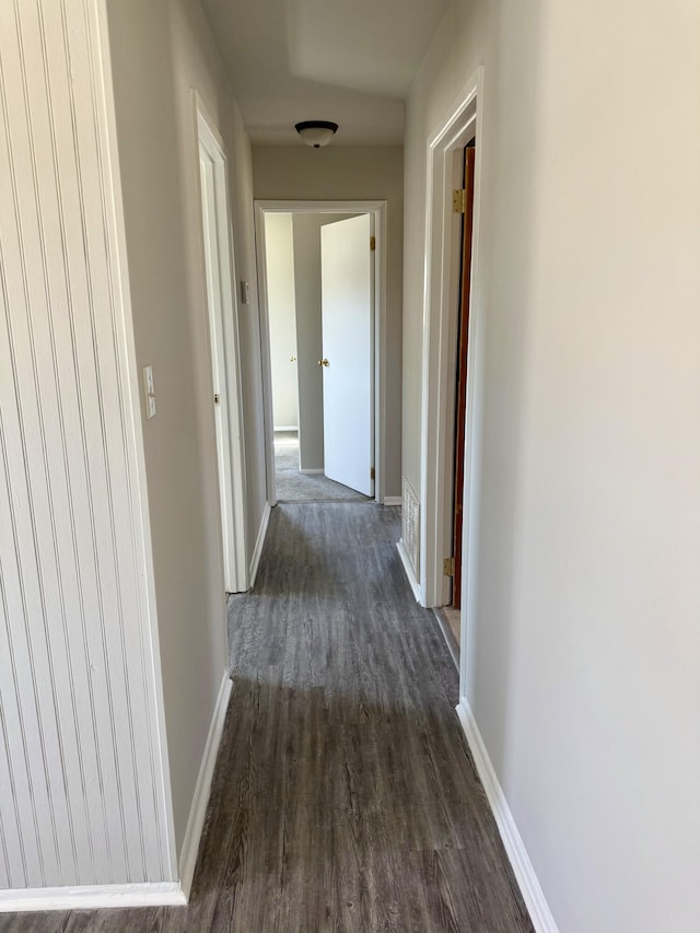 hall with dark wood-type flooring and baseboards