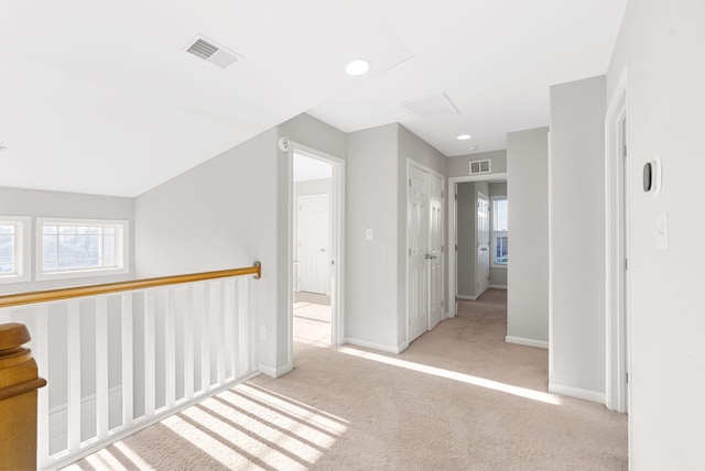 hallway with visible vents, a healthy amount of sunlight, and carpet