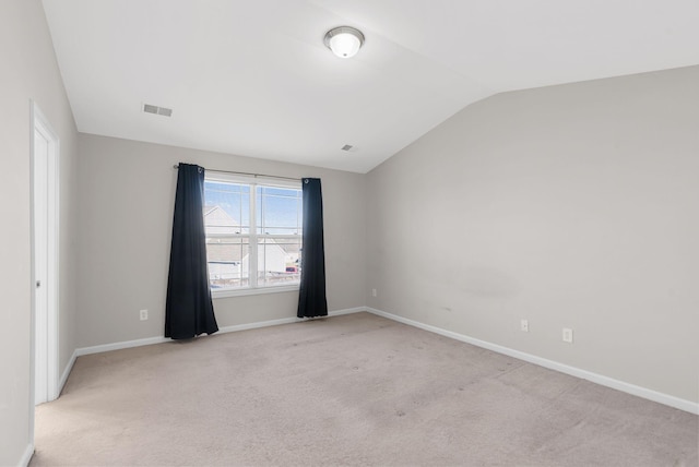 spare room featuring visible vents, light colored carpet, baseboards, and lofted ceiling