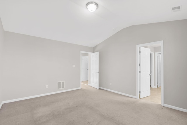 interior space with visible vents, light colored carpet, baseboards, and lofted ceiling