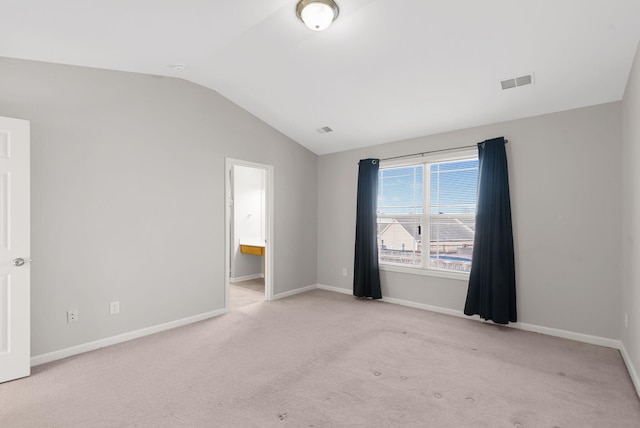 carpeted empty room featuring lofted ceiling, baseboards, and visible vents