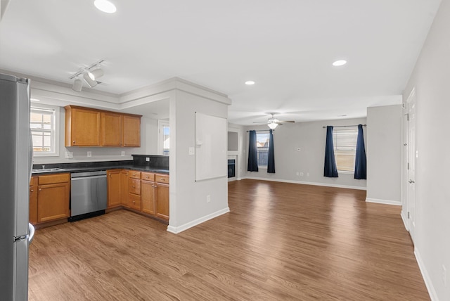 kitchen with a fireplace, stainless steel appliances, light wood-style floors, dark countertops, and open floor plan