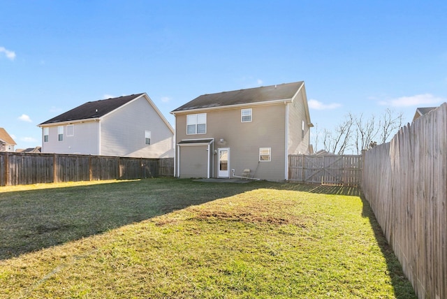 back of house with a yard and a fenced backyard