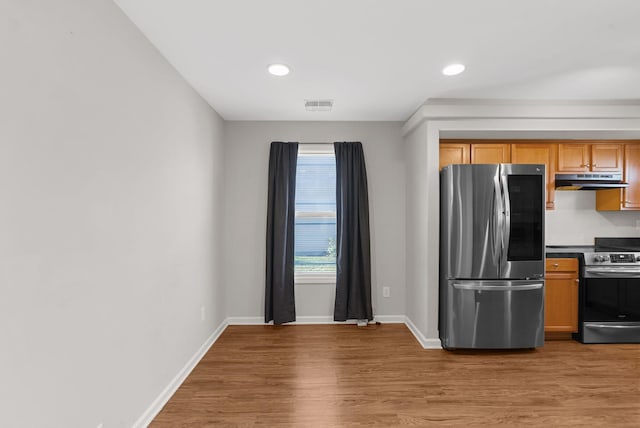 kitchen featuring under cabinet range hood, stainless steel appliances, visible vents, and light wood-style flooring