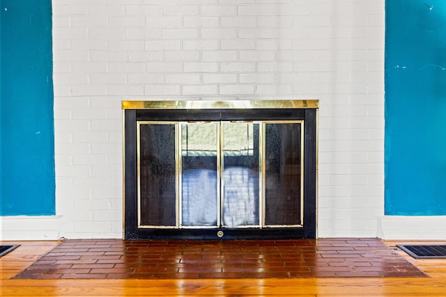 room details with a glass covered fireplace, wood finished floors, and visible vents