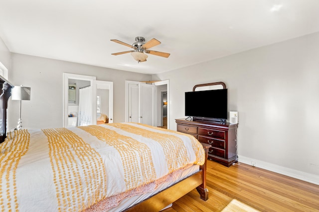 bedroom featuring ceiling fan, light wood finished floors, baseboards, and ensuite bath