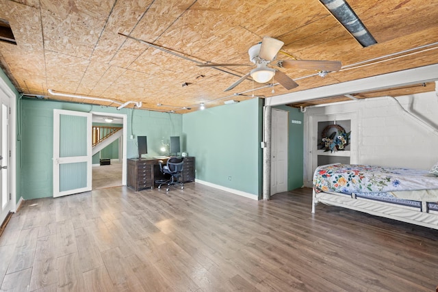 unfurnished bedroom featuring concrete block wall and wood finished floors