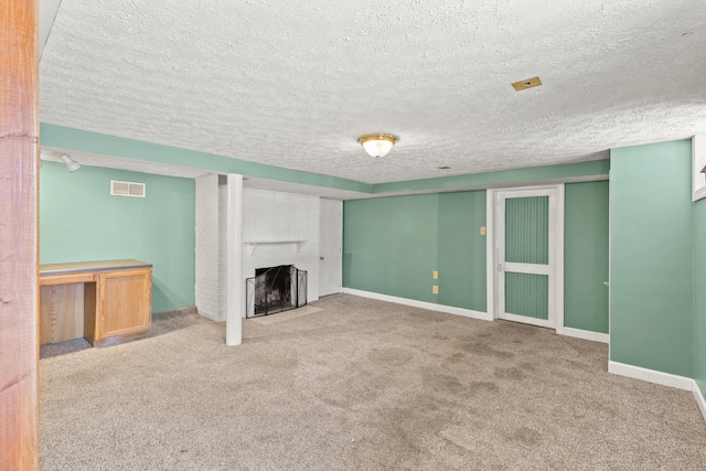 unfurnished living room featuring visible vents, baseboards, carpet flooring, a fireplace, and a textured ceiling