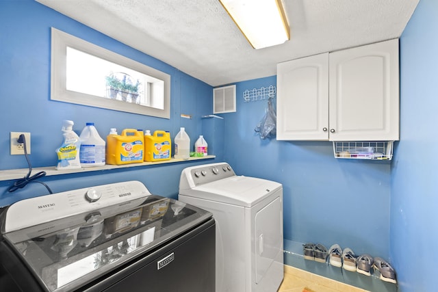 laundry area with washer and clothes dryer, visible vents, cabinet space, and a textured ceiling