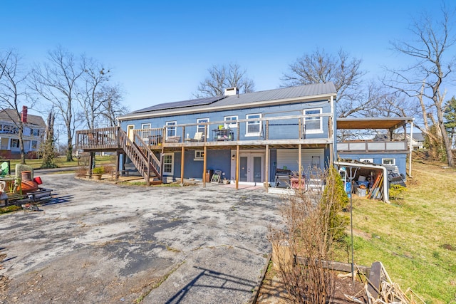rear view of property with a deck, metal roof, a chimney, stairs, and french doors