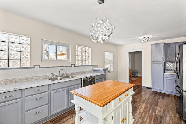 kitchen with an inviting chandelier, a sink, stainless steel appliances, gray cabinetry, and dark wood-style floors