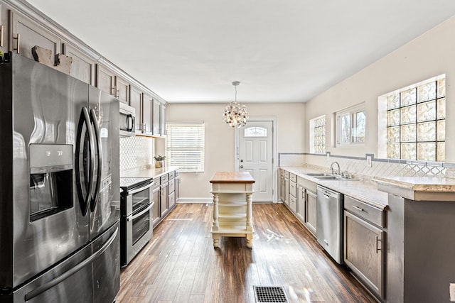 kitchen with visible vents, dark wood-type flooring, a sink, stainless steel appliances, and light countertops