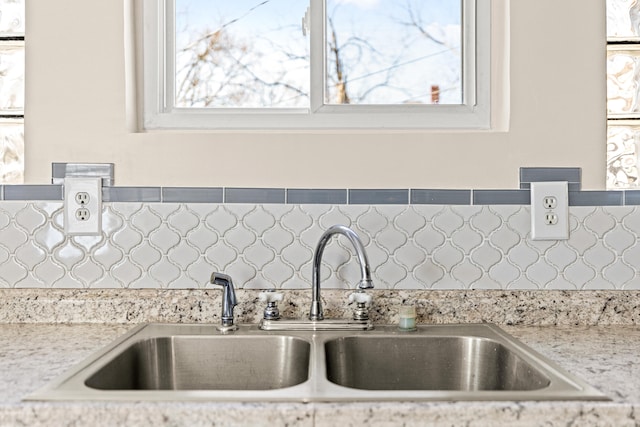 interior details featuring tasteful backsplash, light stone countertops, and a sink