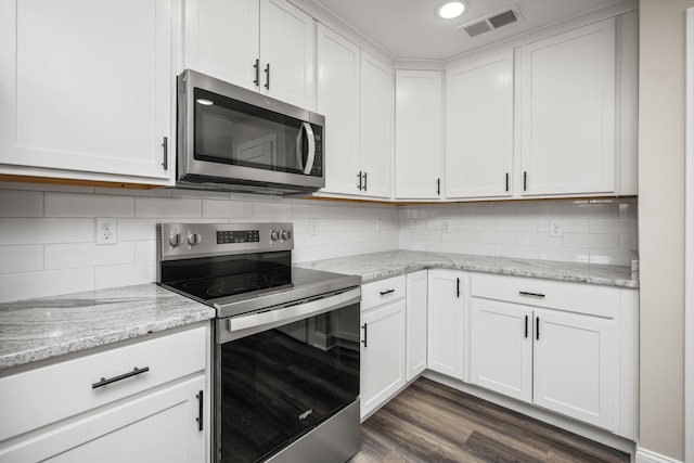 kitchen with light stone counters, visible vents, dark wood finished floors, white cabinets, and appliances with stainless steel finishes