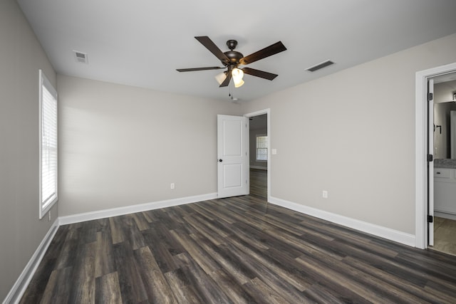 unfurnished bedroom featuring visible vents, multiple windows, and dark wood-style flooring