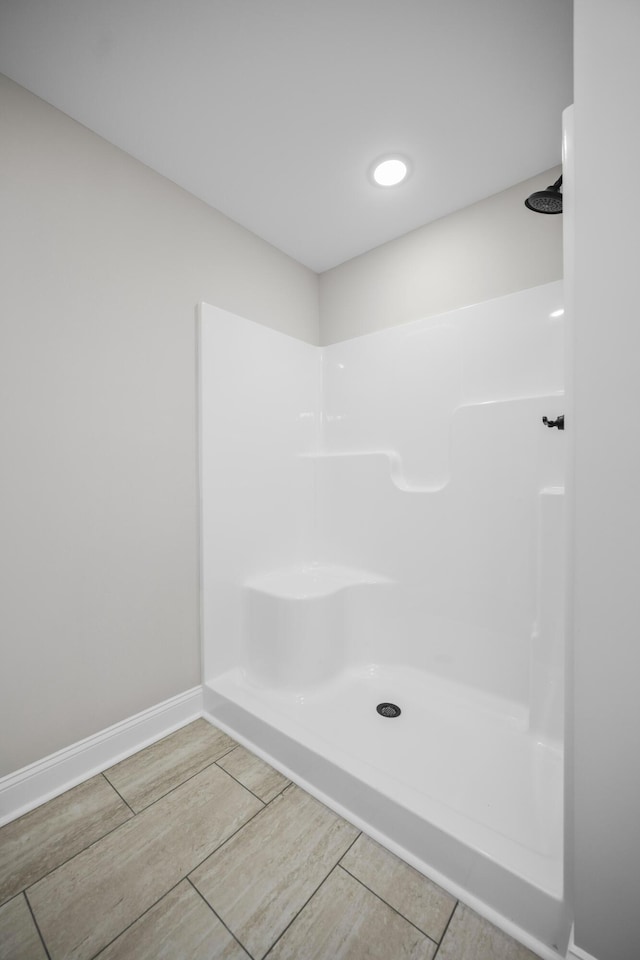 full bath featuring baseboards, walk in shower, and wood finished floors