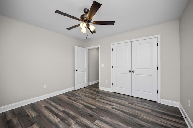 unfurnished bedroom featuring dark wood finished floors, a closet, baseboards, and a ceiling fan