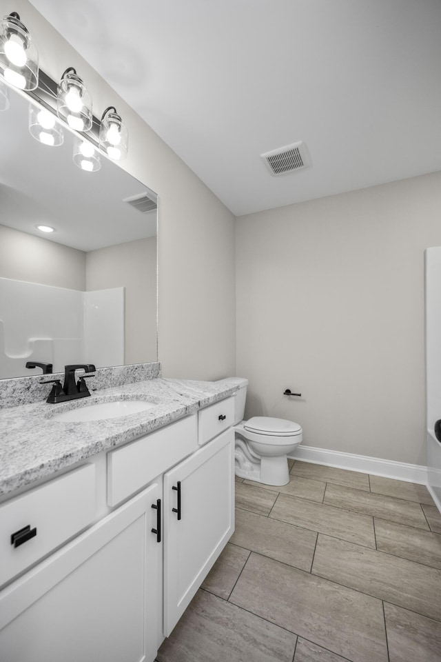 bathroom with visible vents, toilet, vanity, and baseboards