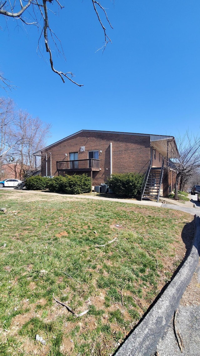 view of front of house featuring brick siding, a wooden deck, and a front lawn