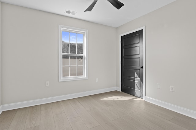 empty room with light wood-style flooring, a ceiling fan, visible vents, and baseboards