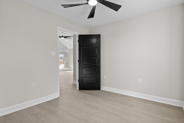 spare room with baseboards, light wood finished floors, and ceiling fan